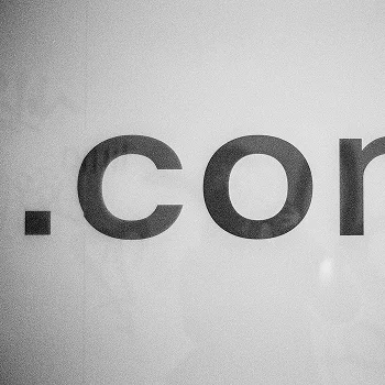 Close-up of the text ".com" in bold, minimalist black font on a light background, conveying a digital or web presence.