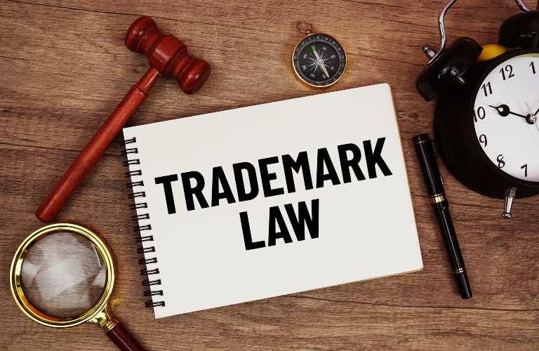 Trademark Law message written on notepad with alarm clock, wood gavel and magnifying glass